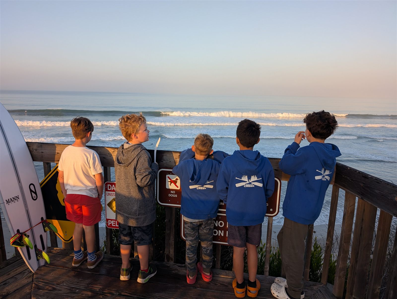 Circle boys watching the sunset and surf from a beach bluff
