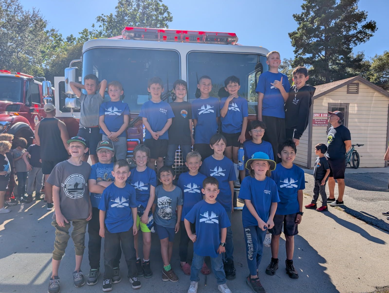 Circle group photo in front of a fire truck at a local community event